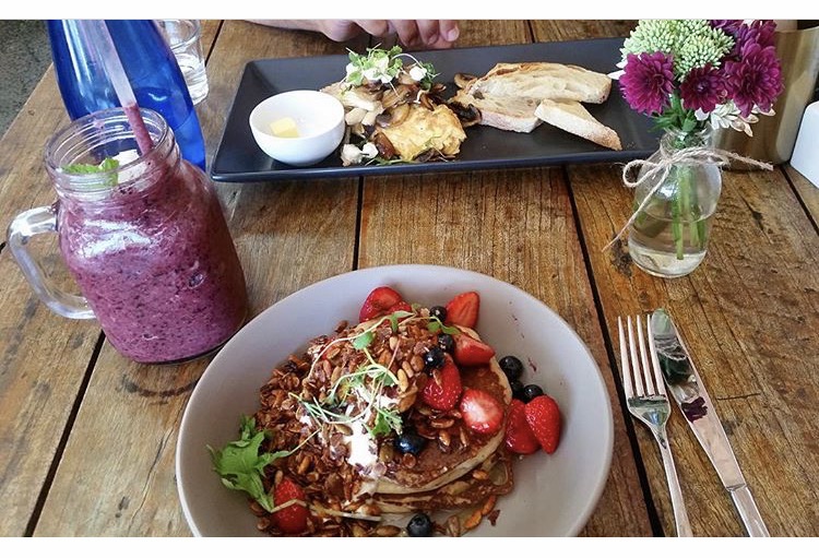 Berry smoothie in a jar with pancakes and fresh flowers