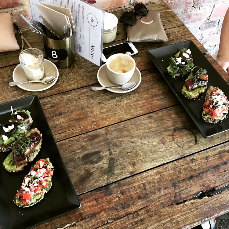 Smashed avo bruschetta and coffees on a rustic table