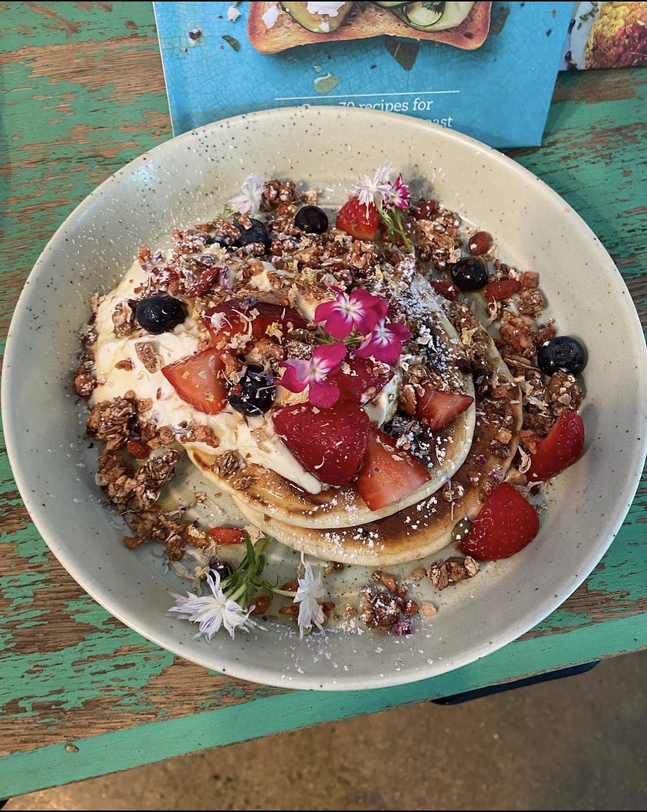 Pancake stack with granola, fresh berries and edible flowers