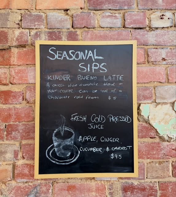 The Seasonal Sips chalkboard on the café’s brick wall